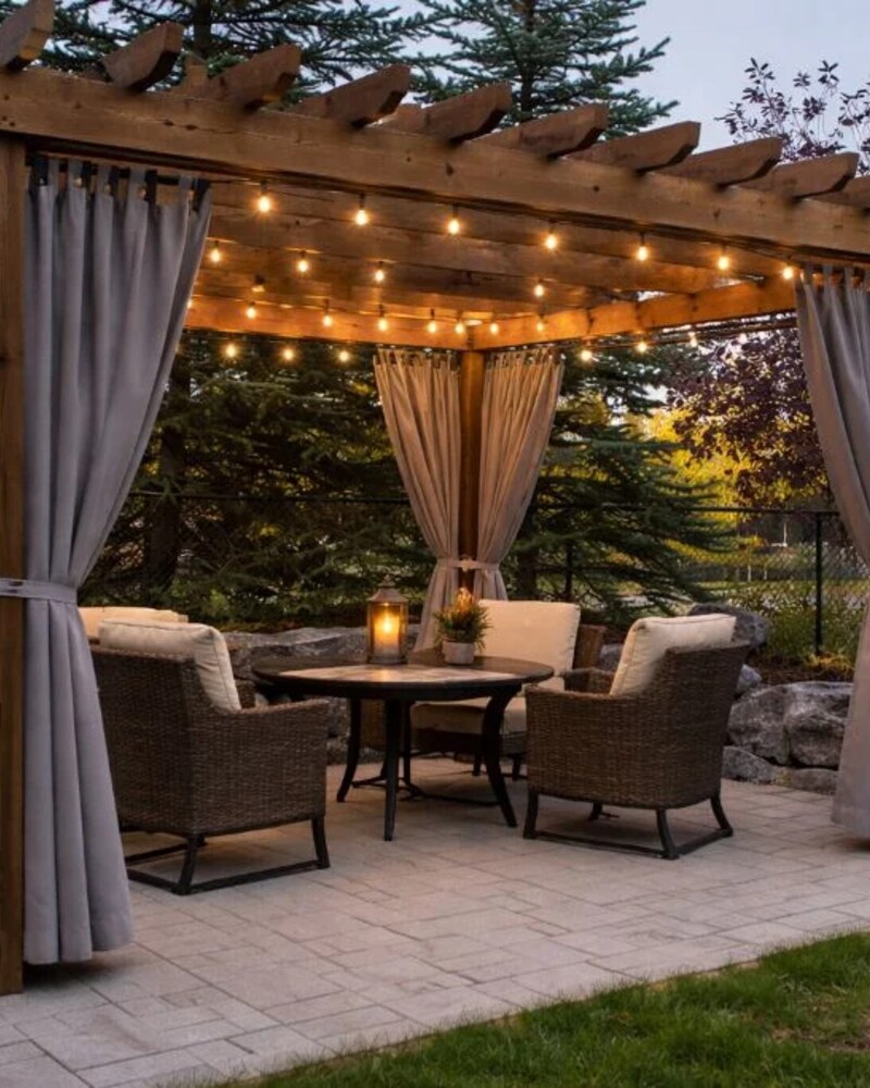 Cedar pergola with string lights and curtains
